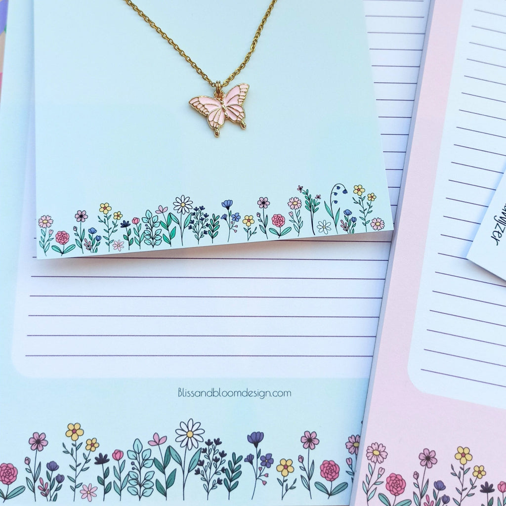 Product stack van halsketting en notitieboekjes in pasteltinten met bloemetjes en vlinder